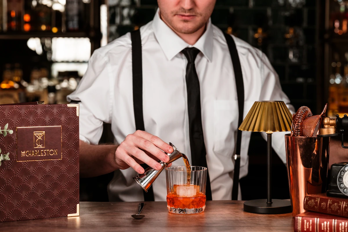 A bartender pouring a drink at the bar