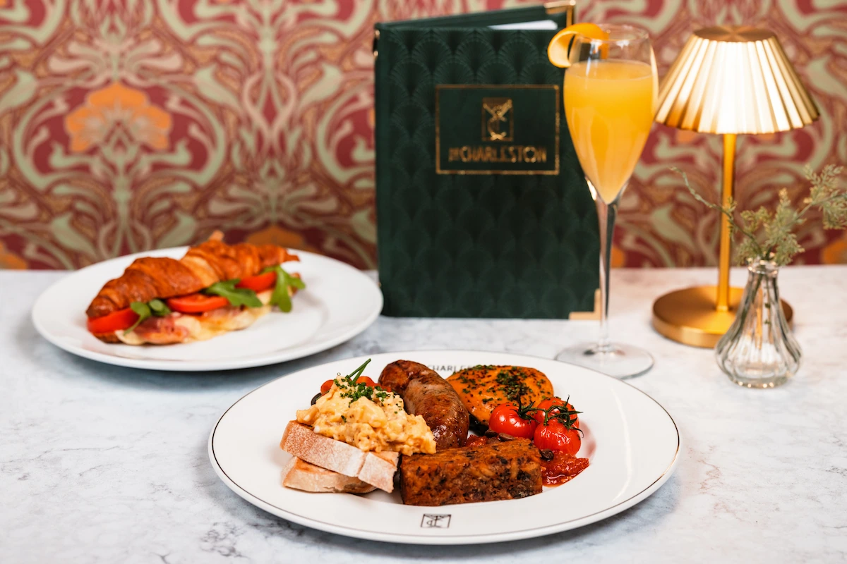 Two plates of food, a full english breakfast and a croissant sandwich