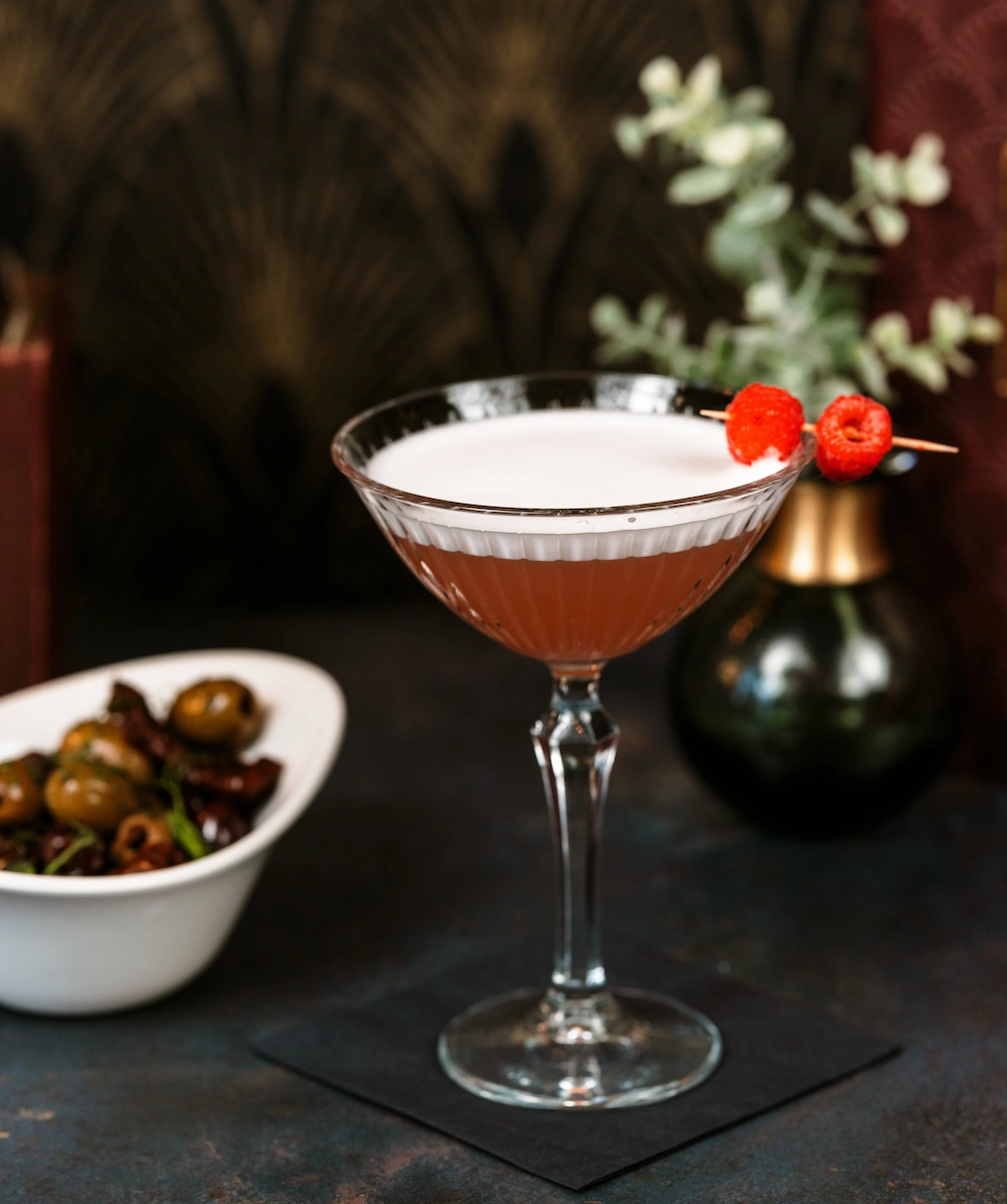 A french martini in a glass, garnished with raspberries
