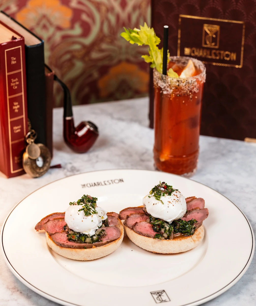 A dish with steak benedict, paired with a bloody mary drink